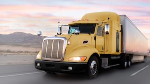 a yellow truck driving down a road at dusk