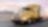 a yellow truck driving down a road at dusk