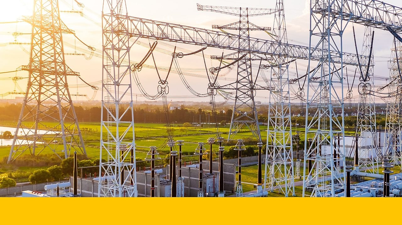 Poste électrique avec lignes de transmission haute tension interconnectées et équipements au coucher du soleil.