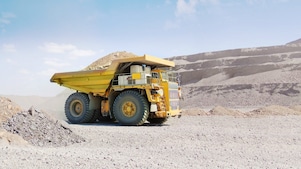 Camion benne jaune roulant sur du gravier