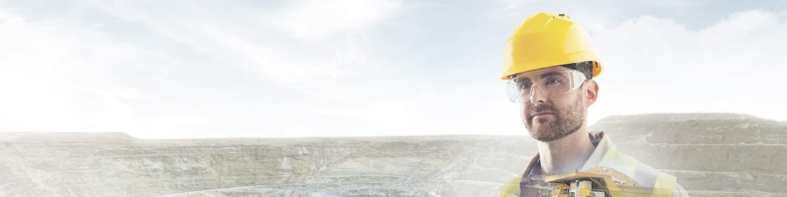 Travailleur portant un casque jaune transposé sur un fond de falaises et un gros camion jaune