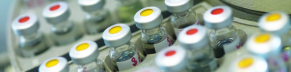 Rangées de fioles pharmaceutiques dans un support, avec un point rouge ou jaune sur le couvercle