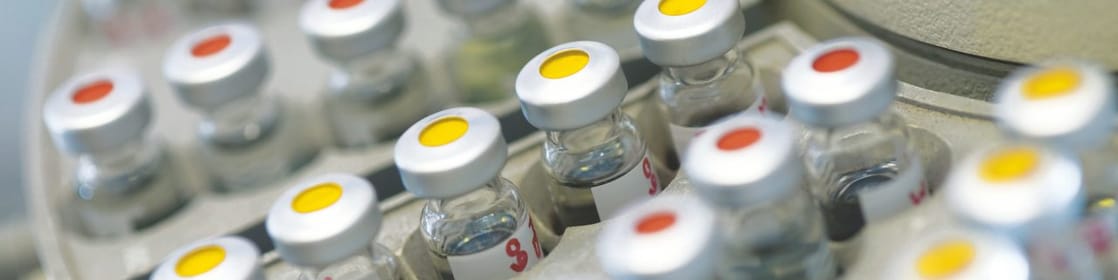 Rangées de fioles pharmaceutiques dans un support, avec un point rouge ou jaune sur le couvercle
