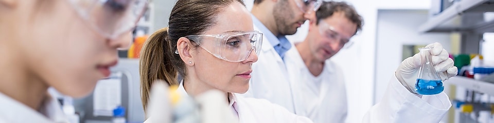 Techniciens au labo avec blouses blanches et lunettes de protection, manipulant des échantillons