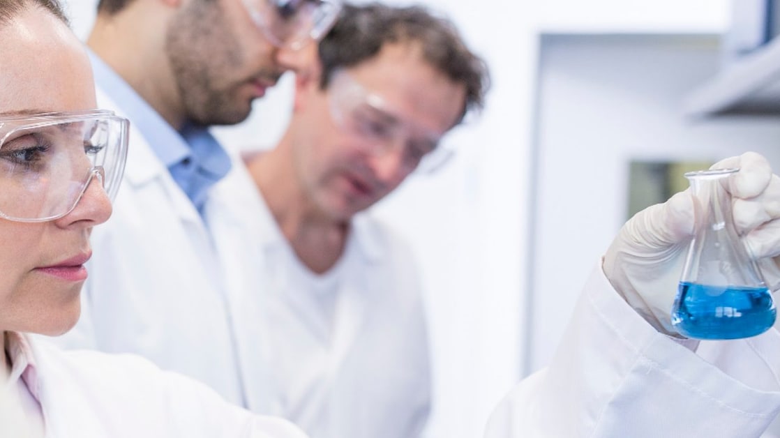 Techniciens au labo avec blouses blanches et lunettes de protection, manipulant des échantillons