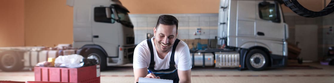 Des mécaniciens poids lourds remplissent des documents avant l’entretien d’un véhicule dans un atelier de réparation