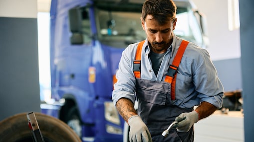 Mécanicien utilisant des outils pour travailler sur un camion dans un atelier pour poids lourds.