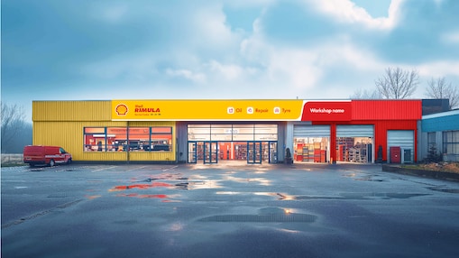 Vue d’un atelier de camions aux couleurs de Shell. Le bâtiment présente une façade jaune et rouge avec le logo Shell et l’inscription « Shell Rimula » bien visible.