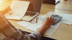 Une personne travaille sur un bureau et vérifie une calculatrice.