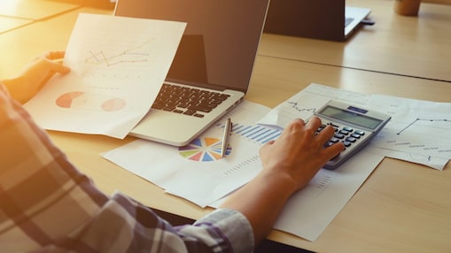 Une personne travaille sur un bureau et vérifie une calculatrice.