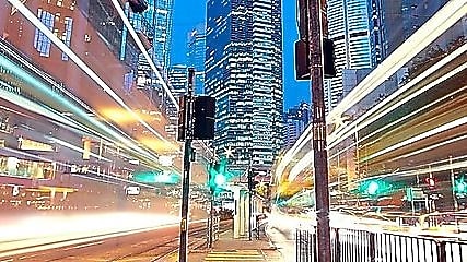 A city scape at night with trailing lights from cars going by.