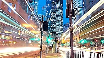 A city scape at night with trailing lights from cars going by.