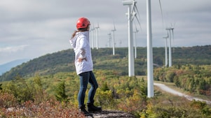 A female Shell employee standing in front of a wind turbine.