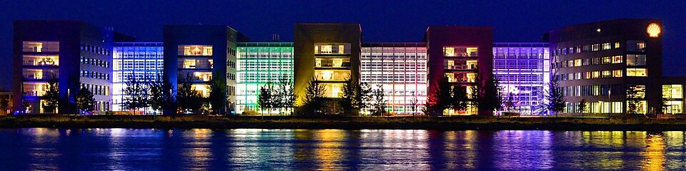 Un ensemble de bâtiments de bureaux allumés se reflète sur l'eau la nuit