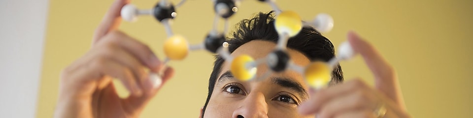 Jeune homme examinant un modèle de molécule