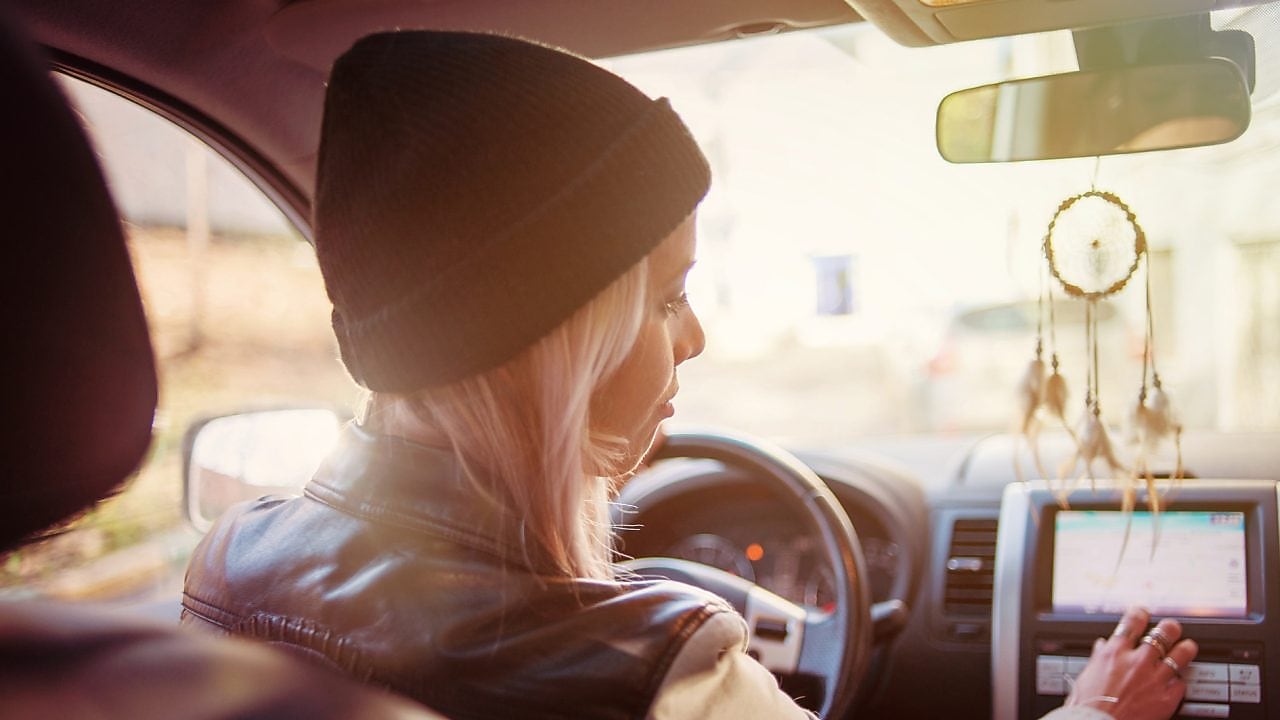 Une jeune femme consulte les instructions du GPS de sa voiture