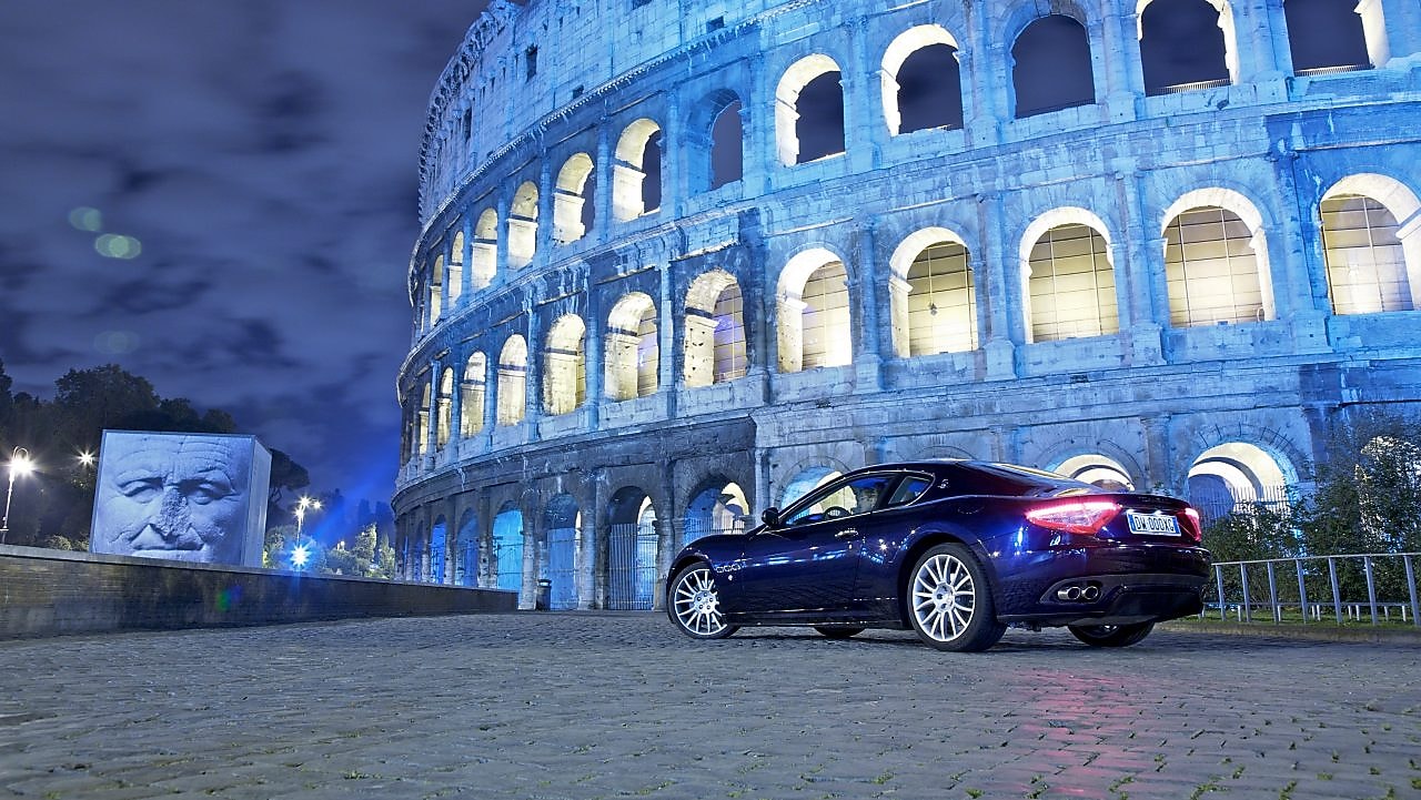 Une voiture noire la nuit devant le Colisée