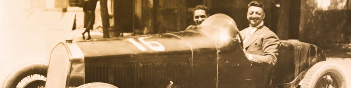 Photo en noir et blanc d'Enzo Ferrari assis dans l'une des premières Ferrari