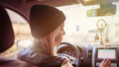 Une jeune femme consulte les instructions du GPS de sa voiture