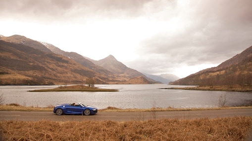 Une voiture sur la route à côté d'un lac de montagne