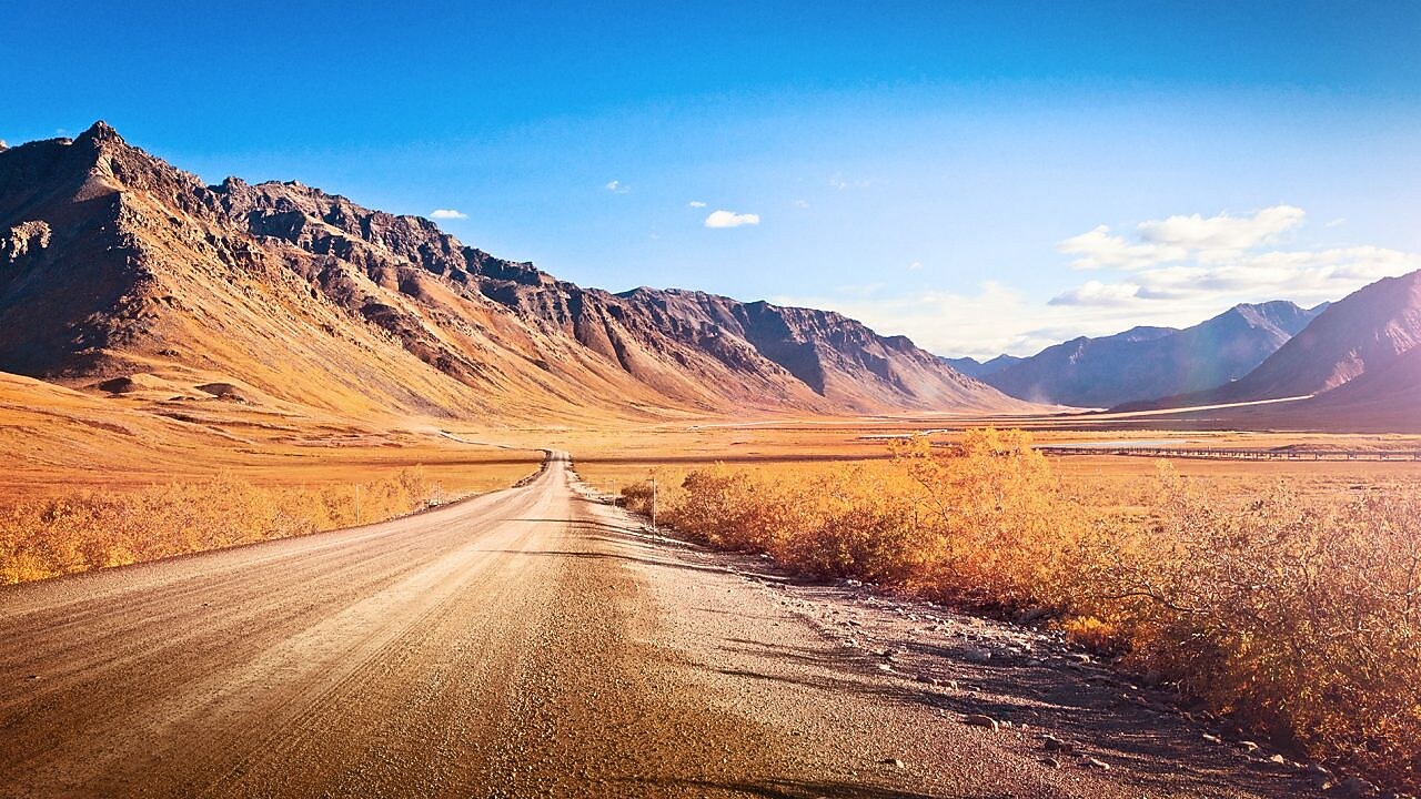 Un chemin de terre entièrement vide, entouré de montagnes