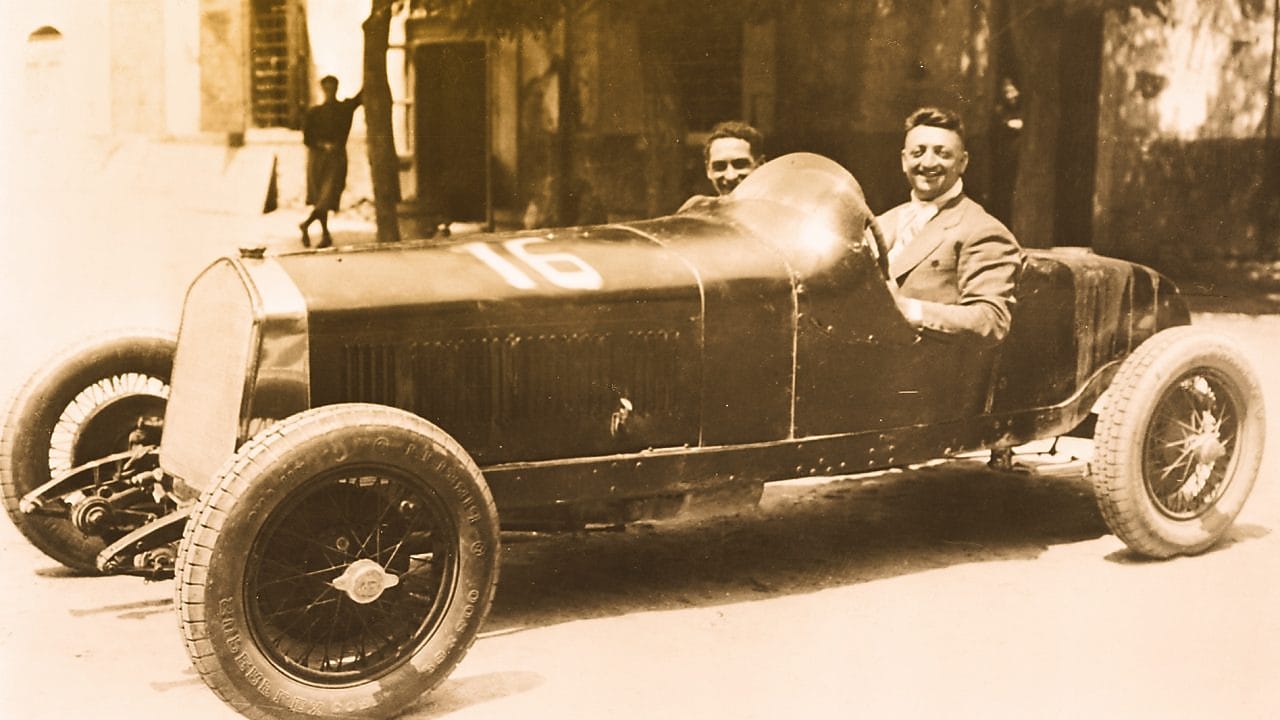 Photo en noir et blanc d'Enzo Ferrari assis dans l'une des premières Ferrari