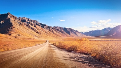 Un chemin de terre entièrement vide, entouré de montagnes