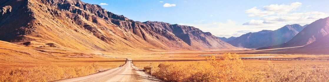 Un chemin de terre entièrement vide, entouré de montagnes