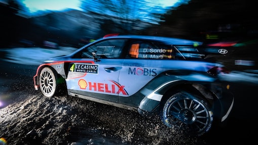 Une voiture de rallye fonce à la tombée de la nuit sur une épreuve du championnat du monde des rallyes
