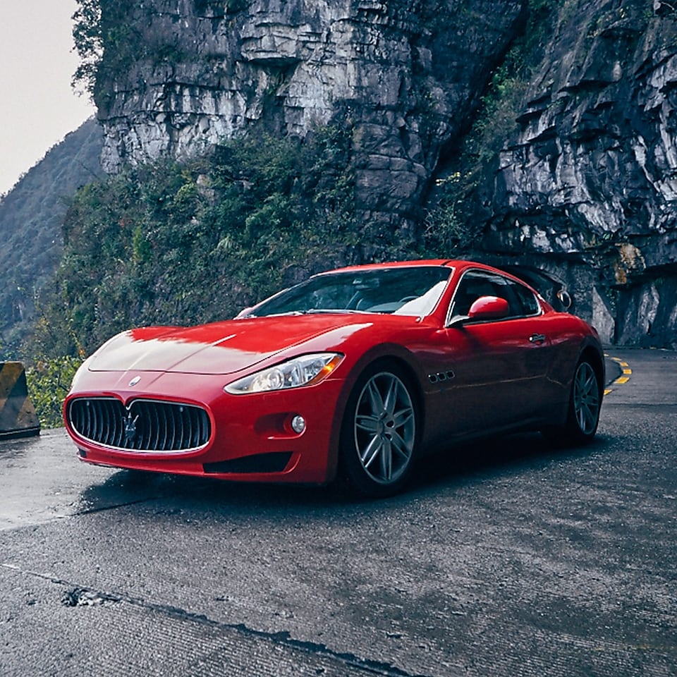 Une Maserati rouge avec le produit Shell Helix Ultra se tient fièrement sur une route de montagne pittoresque