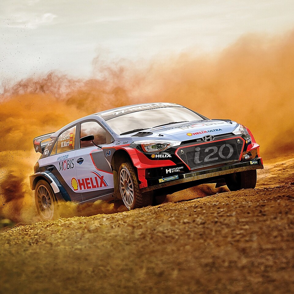 Une voiture Hyundai Motorsport génère un nuage de poussière sur une piste de course, illustrant la grande performance de l’utilisation de Shell Helix Ultra en environnements extrêmes